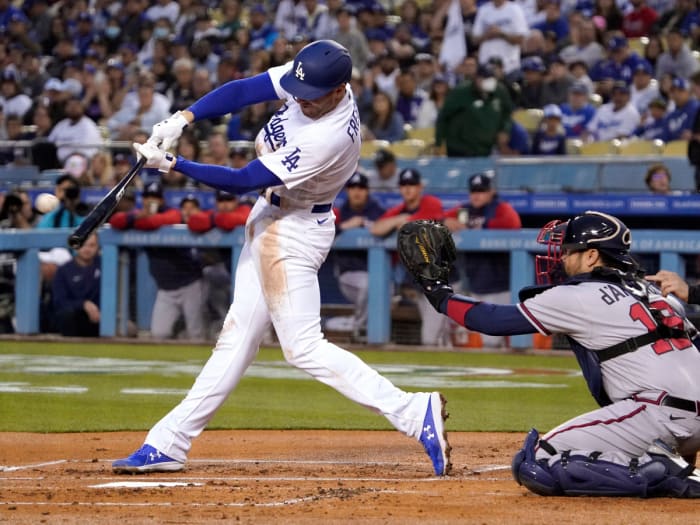 Los Angeles Dodgers’ Freddie Freeman, left, hits a solo home run as Atlanta Braves catcher Travis d’Arnaud watches during the first inning of a baseball game Monday, April 18, 2022, in Los Angeles.